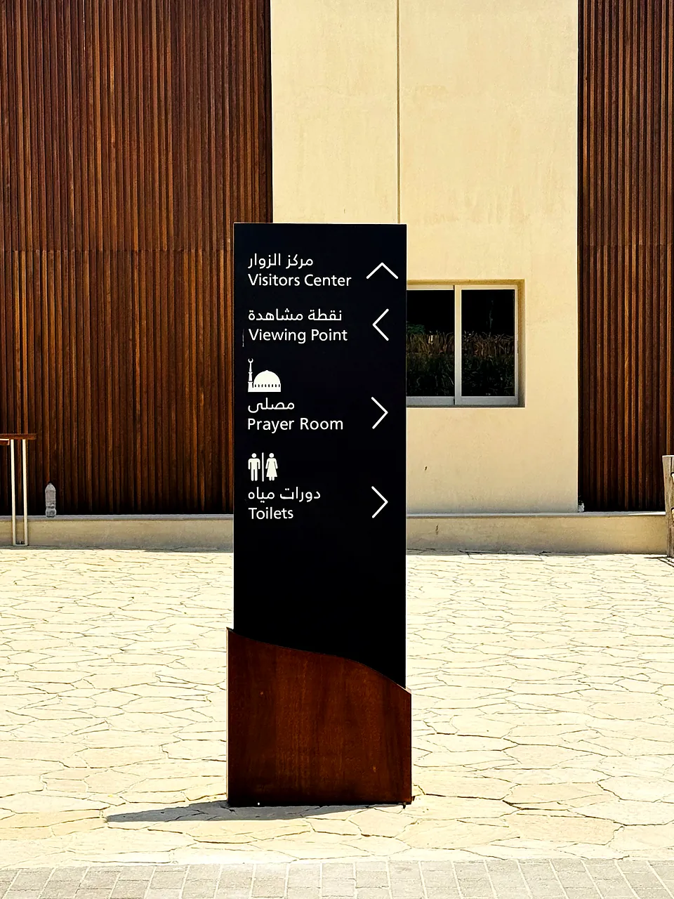 Bilingual Arabic and English wayfinding totem sign with corten steel base at Al Wathba, Abu Dhabi