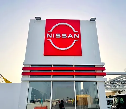 Illuminated Nissan logo pylon and fascia sign at a car showroom in the UAE
