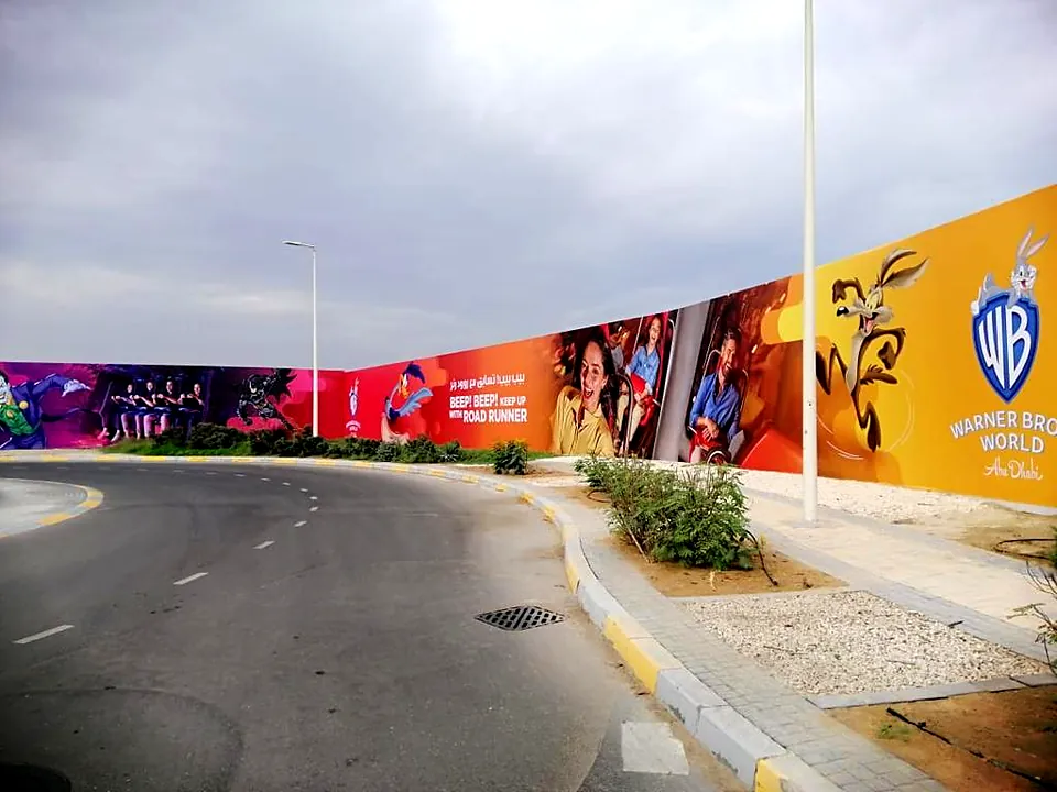 Long roadside hoarding with printed Warner Bros. World artwork on Yas Island, Abu Dhabi